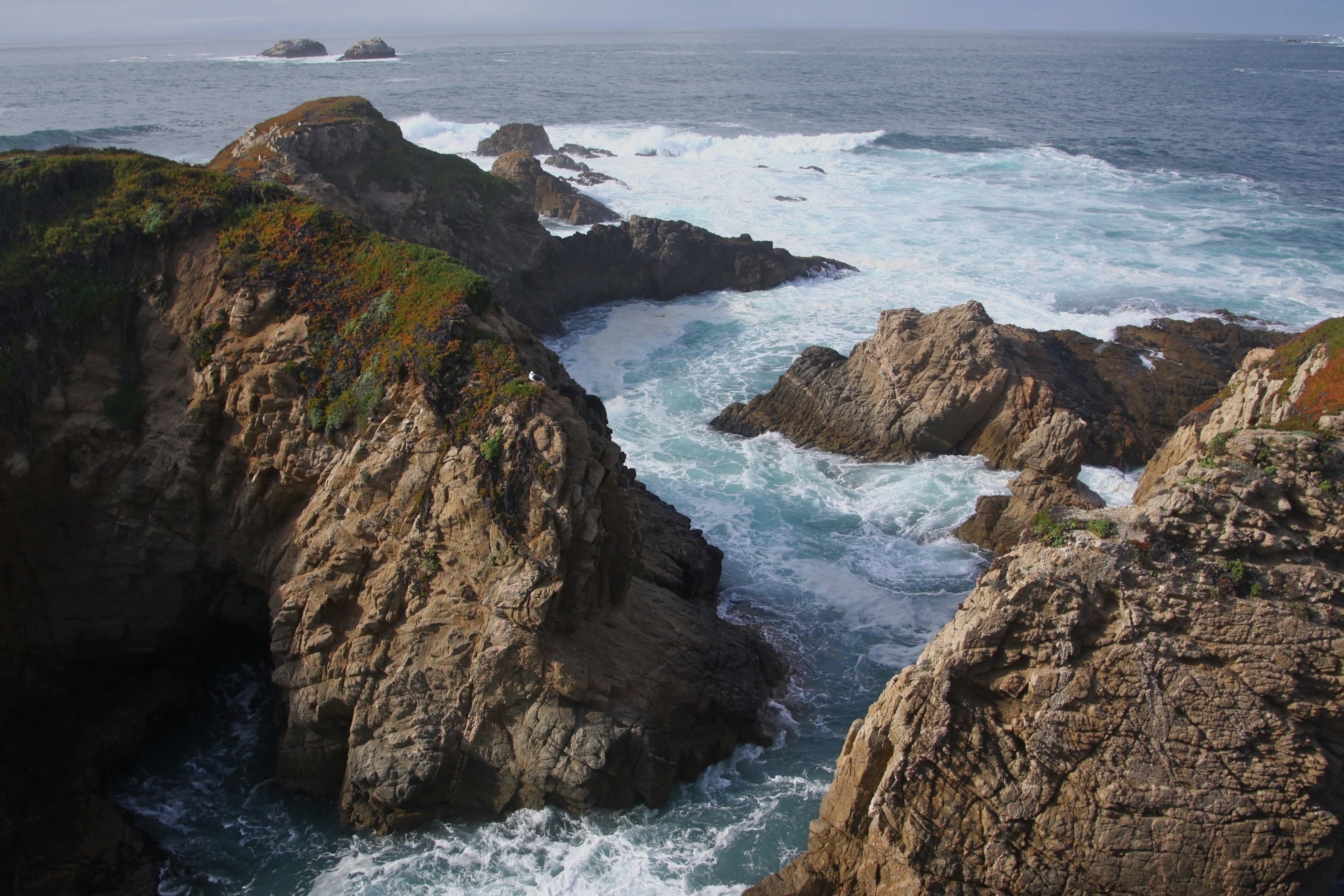 brown rocky mountain beside sea during daytime